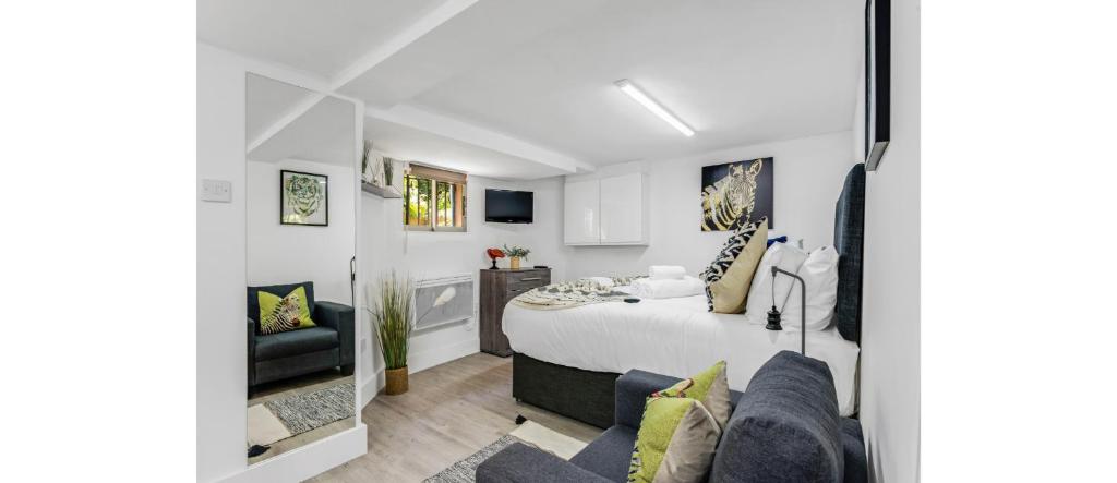 a white bedroom with a bed and a couch at Cosy Little Flat - Perfect Base for Explorers in London