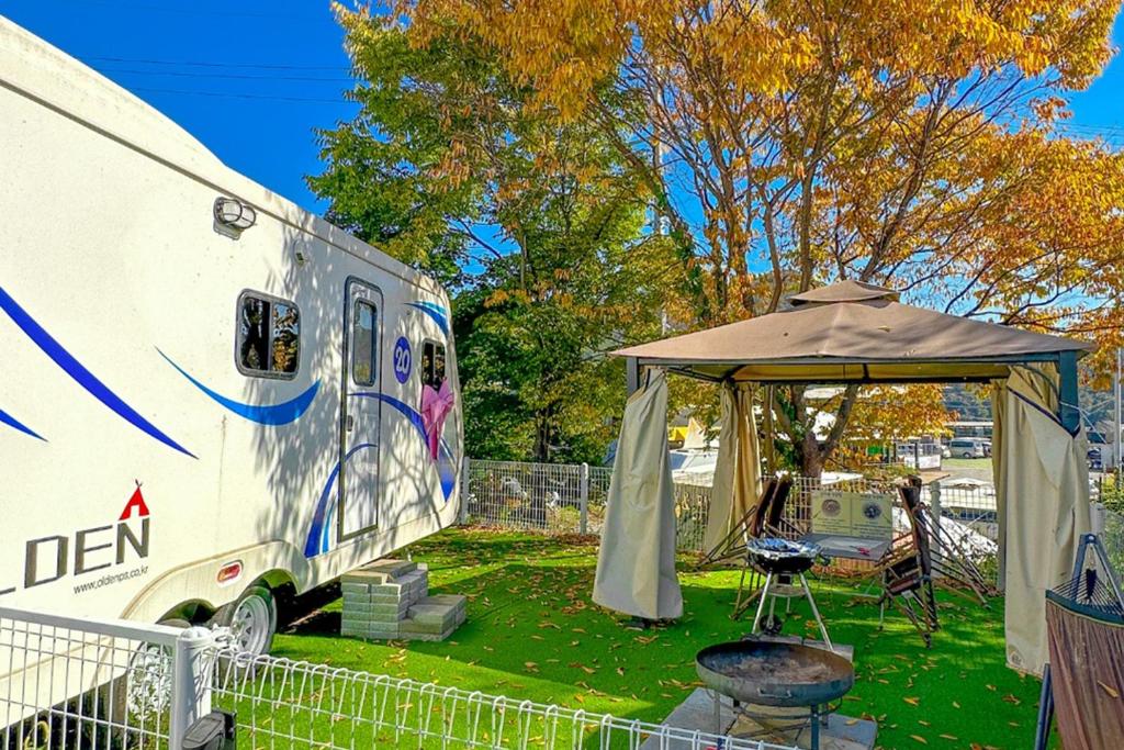 uma caravana com uma tenda, uma mesa e um guarda-chuva em Gapyeong Olden Caravan & Pension - Pet Friendly em Gapyeong