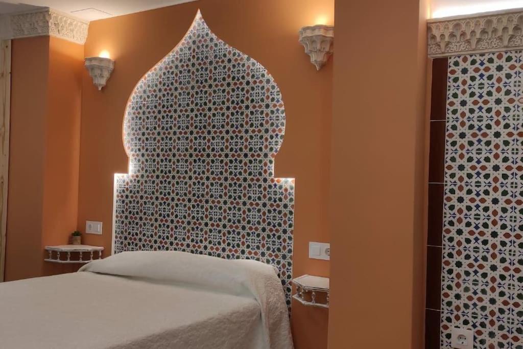 a bedroom with a bed and a moroccan patterned wall at Al-Andalus hause a 9min. del centro en metro in San Juan de Aznalfarache