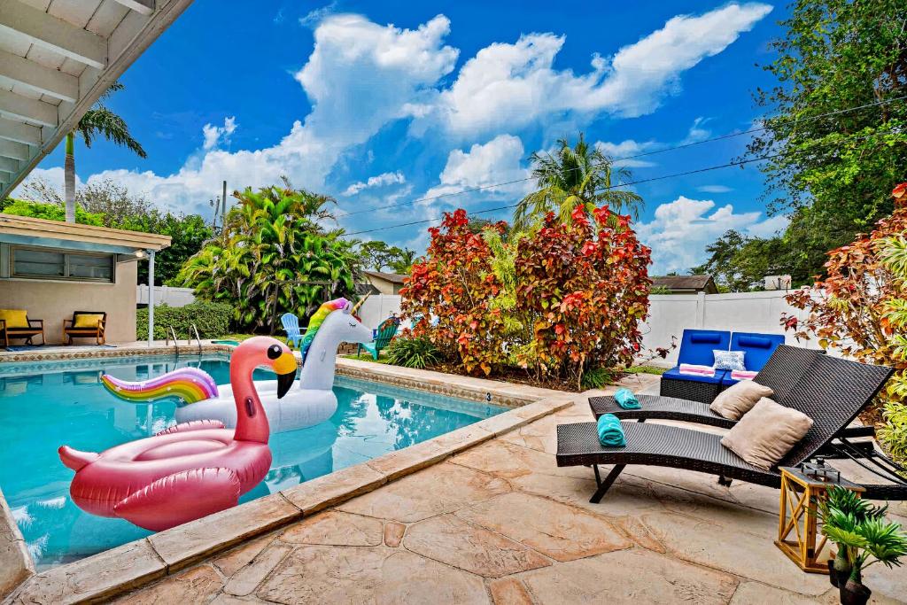 a swimming pool with two inflatable swans and a pool at Music Lovers Villa, 4BD, 3BA, Pool, Game Room Outdoor Projector in Pembroke Pines
