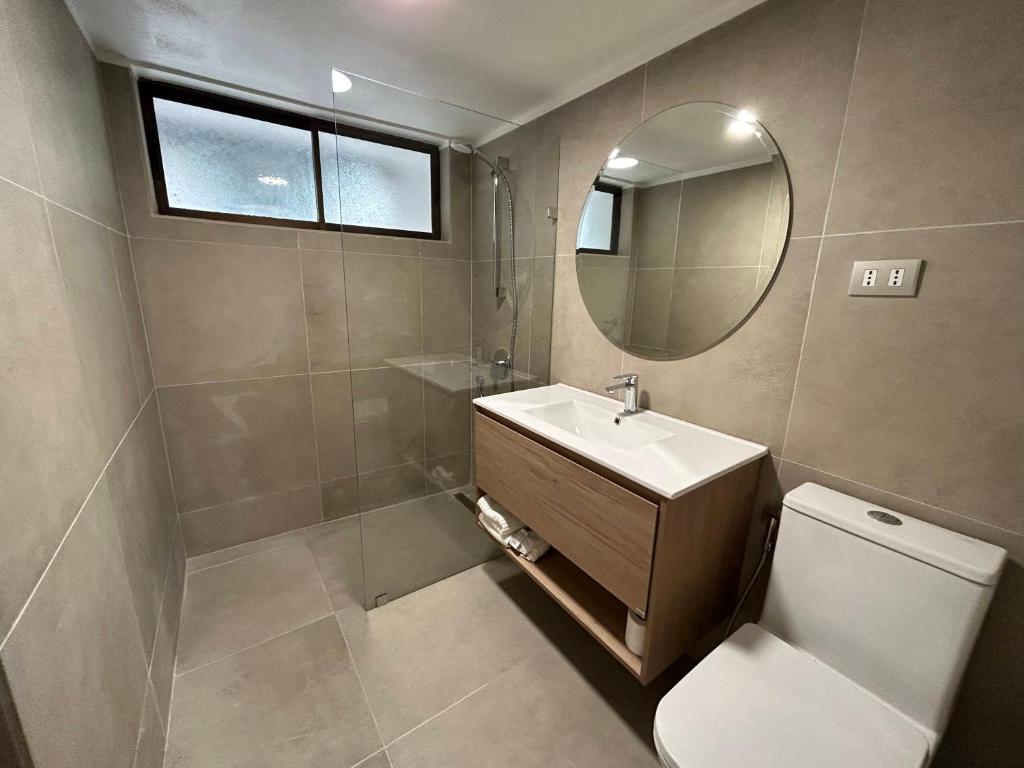 a bathroom with a toilet and a sink and a mirror at Alto Las Condes Apartments in Santiago
