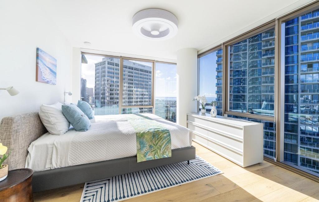 a bedroom with a bed and large windows at Semprose Sky Ala Moana in Honolulu