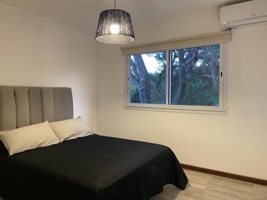 een slaapkamer met een zwart bed en een raam bij Duplex del Parque y Balneario in Necochea