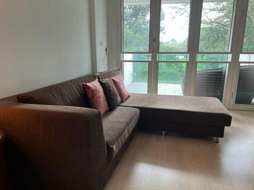 a brown couch in a living room with a large window at Spacious Garden Bungalow Escape in Subang Jaya