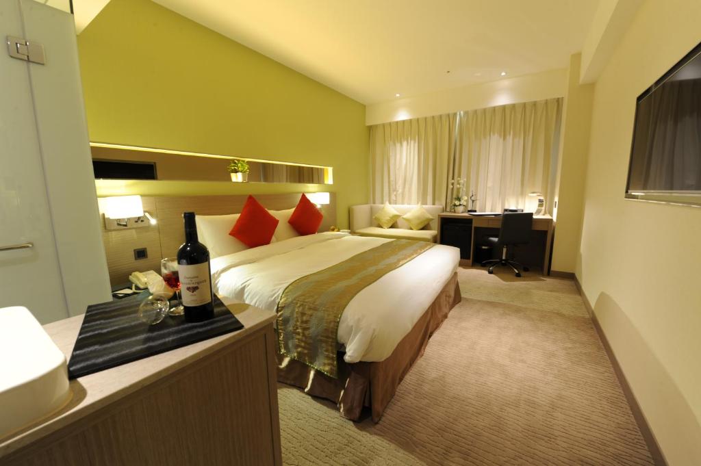 a hotel room with a bed and a bottle of wine at Kaohsiung International Plaza in Kaohsiung
