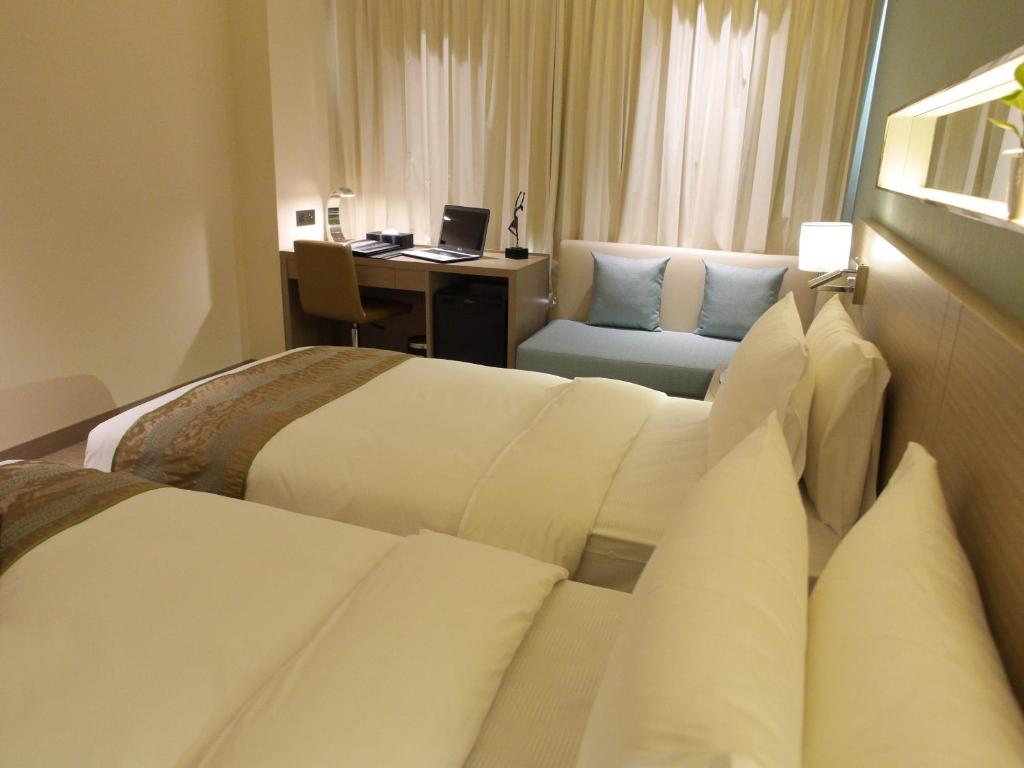 a hotel room with two beds and a desk at Kaohsiung International Plaza in Kaohsiung