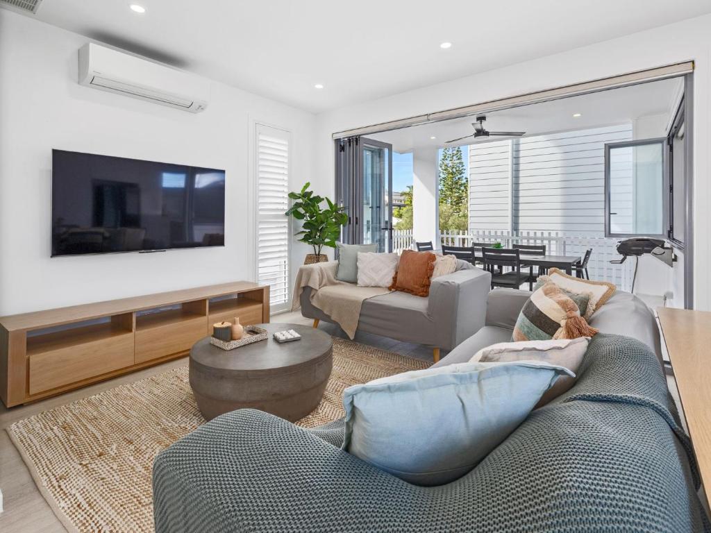 a living room with a couch and a tv at Serenity Sands Townhouse in Kingscliff