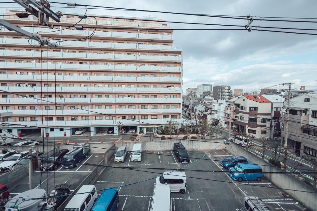 a parking lot with cars parked in front of a large building at 北田辺 4階 in Osaka