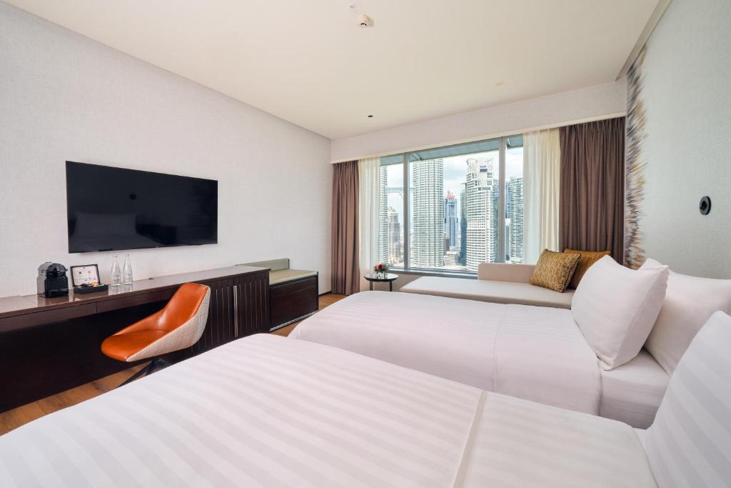 A bright twin room with two beds, a wall-mounted television, a work chair, and a city view.