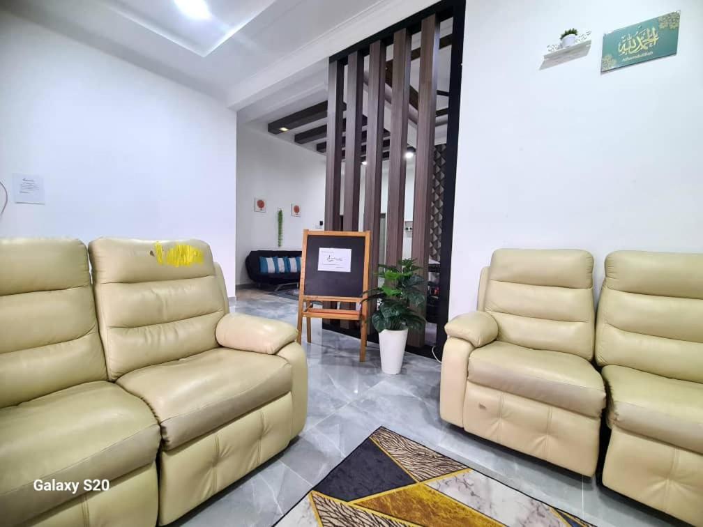 ein Wohnzimmer mit 2 Stühlen und einem Sofa in der Unterkunft Homestay Husna in Dungun