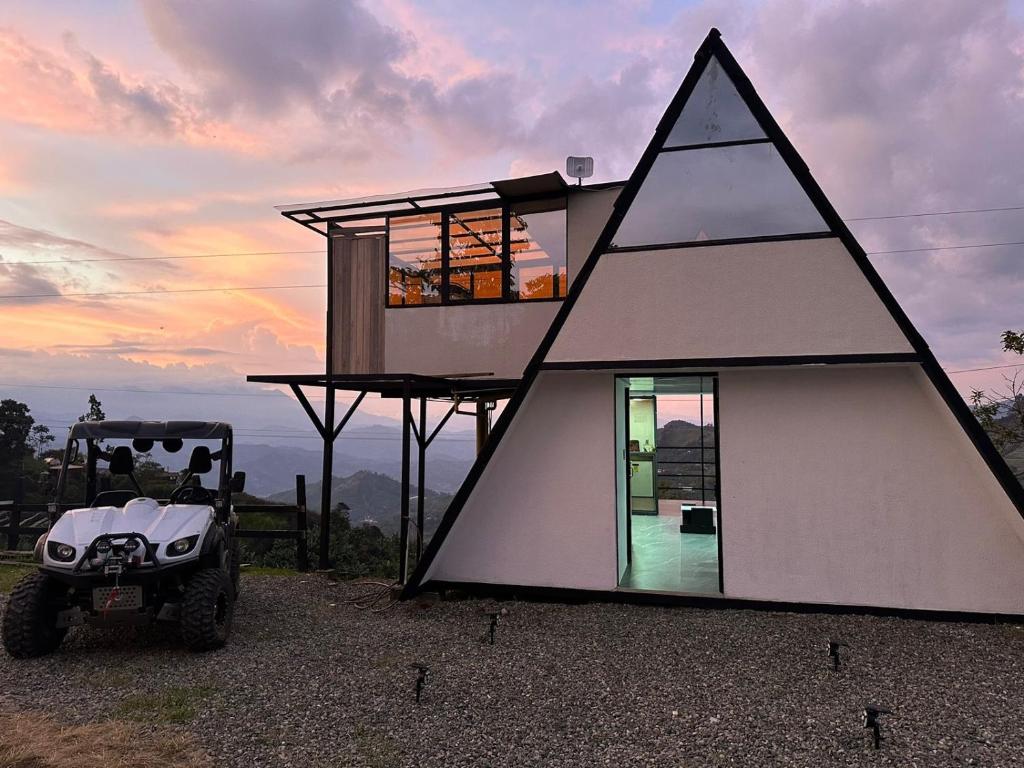 a triangular house with a golf cart in front of it at De las flores Glamping Alpino in Jardin