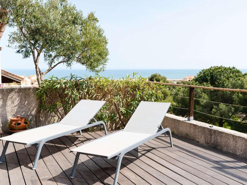 duas cadeiras brancas num deque com o oceano ao fundo em Villa Fleury-Saint-Pierre-la-Mer, 4 pièces, 6 personnes - FR-1-409-188 em Fleury