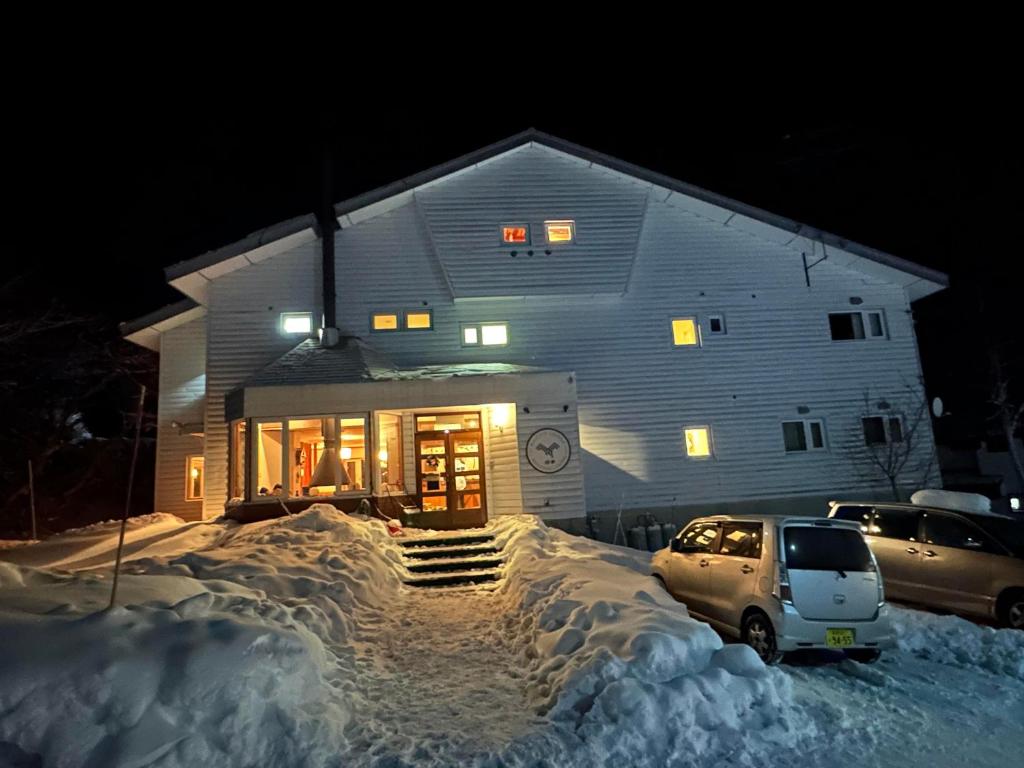 a house with a car parked in the snow at Raicho Lodge Madarao in Iiyama