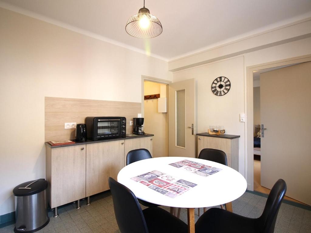 une pièce avec une table et des chaises et une cuisine dans l'établissement Appartement T1 confortable au Mont-Dore pour 2 personnes - FR-1-415-151, à Le Mont-Dore