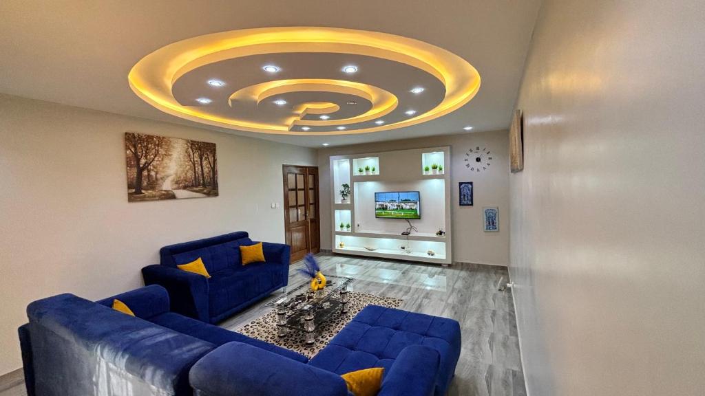 Magnifique appartement meublé à Dakar, Rte de Rufisque في داكار: غرفة معيشة مع أريكة زرقاء وسقف ذهبي