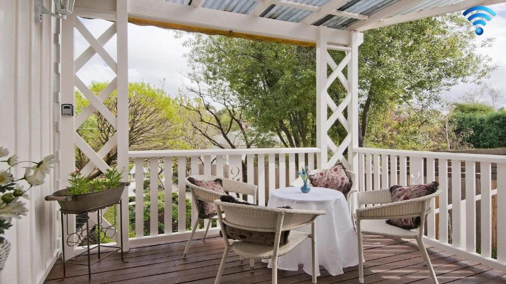 a white porch with a table and chairs on it at Hollyoak Cottage in Bowral