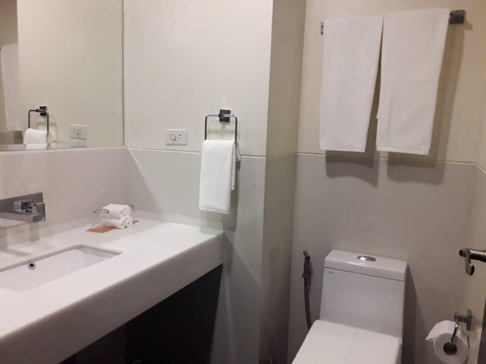 a bathroom with a sink and a toilet and a mirror at MAXX HOTEL MAKATI by MAXIHOME LAND in Manila
