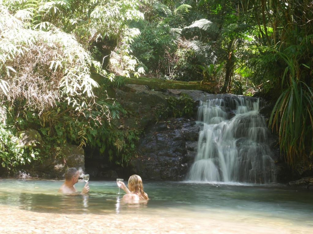 dos personas en el agua frente a una cascada en Fairy Falls - romantic Daintree Rainforest retreat with enchanting waterfall en Cow Bay
