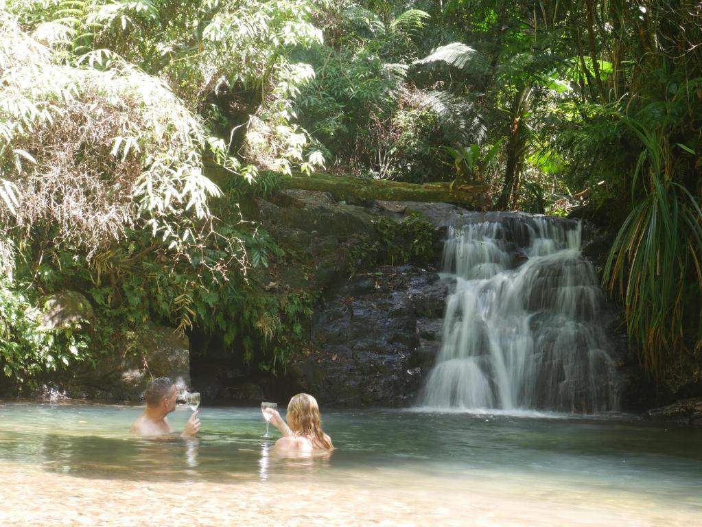 Cow Bay的住宿－Fairy Falls - romantic Daintree Rainforest retreat with enchanting waterfall，瀑布前水中的两个人