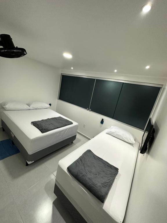 een slaapkamer met 2 bedden en een groot raam bij Quarto privativo com banheiro compartilhado em Pousada recém construída,a 500mts do pátio do forró in Caruaru