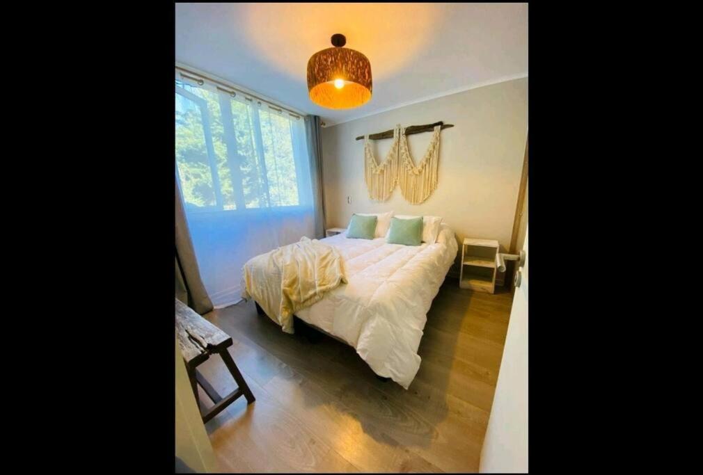 - une chambre avec un lit et un lustre dans l'établissement Departamento hermoso, cómodo, totalmente equipado, à Pucón
