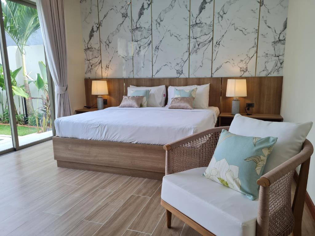 a bedroom with a large bed and a chair at La Ville Phuket Pool Villa in Nai Yang Beach