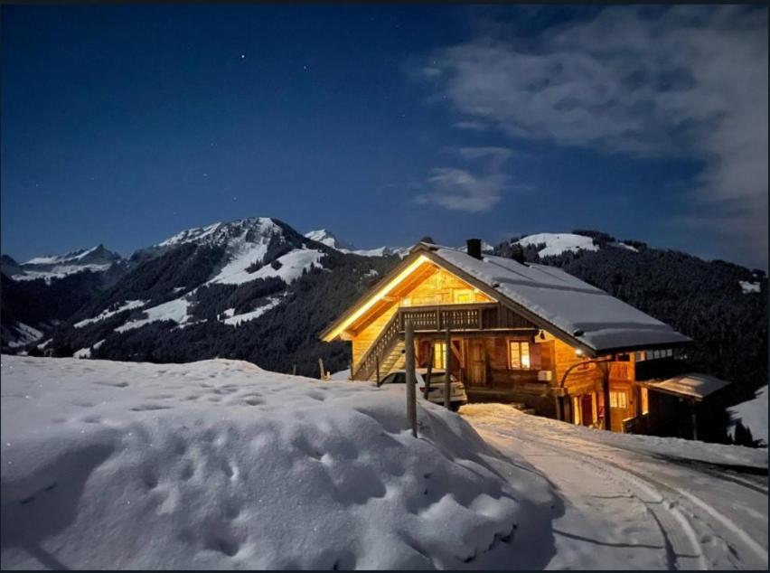 ein Blockhaus im Schnee mit einem Berg in der Unterkunft Mountain Chalet - Panoramic Terraces - Near Gstaad in Devant