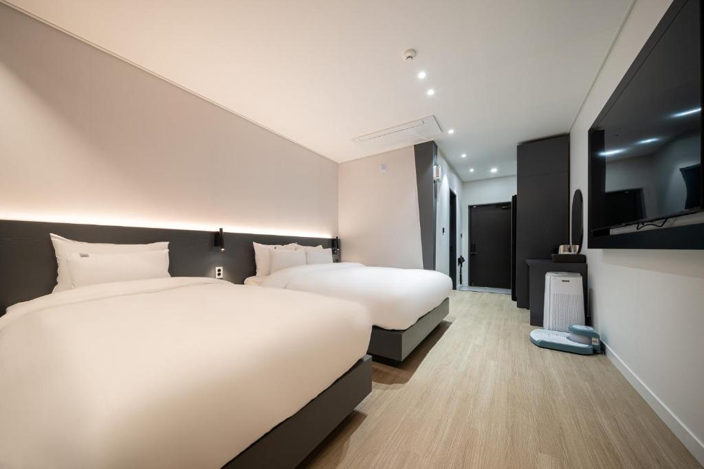 a hotel room with two beds and a tv at Hound Hotel Mokpo Peace Plaza in Mokpo