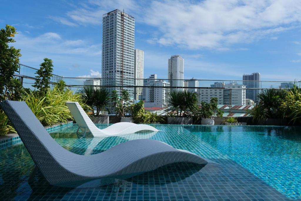 uma piscina com duas cadeiras brancas no topo de um edifício em Em Oi Boutique Hotel em Nha Trang