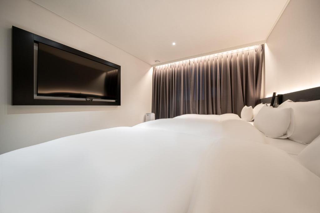 a hotel room with two beds and a flat screen tv at Hound Hotel Mokpo Peace Plaza in Mokpo