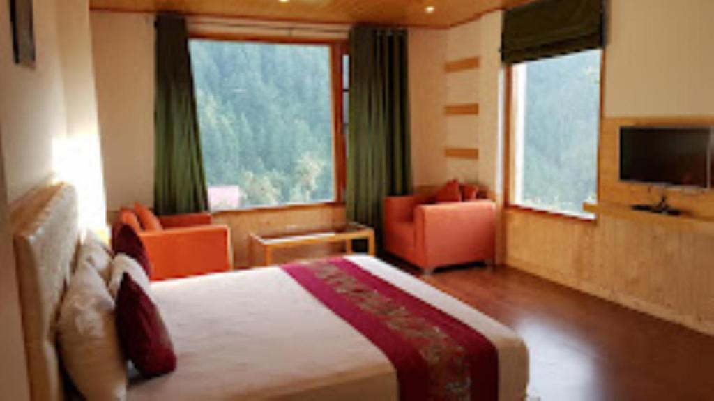 une chambre d'hôtel avec un lit, des chaises et une télévision dans l'établissement Shimla Greens Shimla, à Shimla