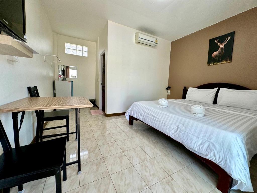 a bedroom with a bed and a table and a desk at Fundee Resort in Chanthaburi