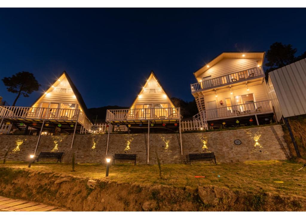 un grupo de tres casas con luces en la noche en Vinyasa Resort , Kanatal, en Kanatal