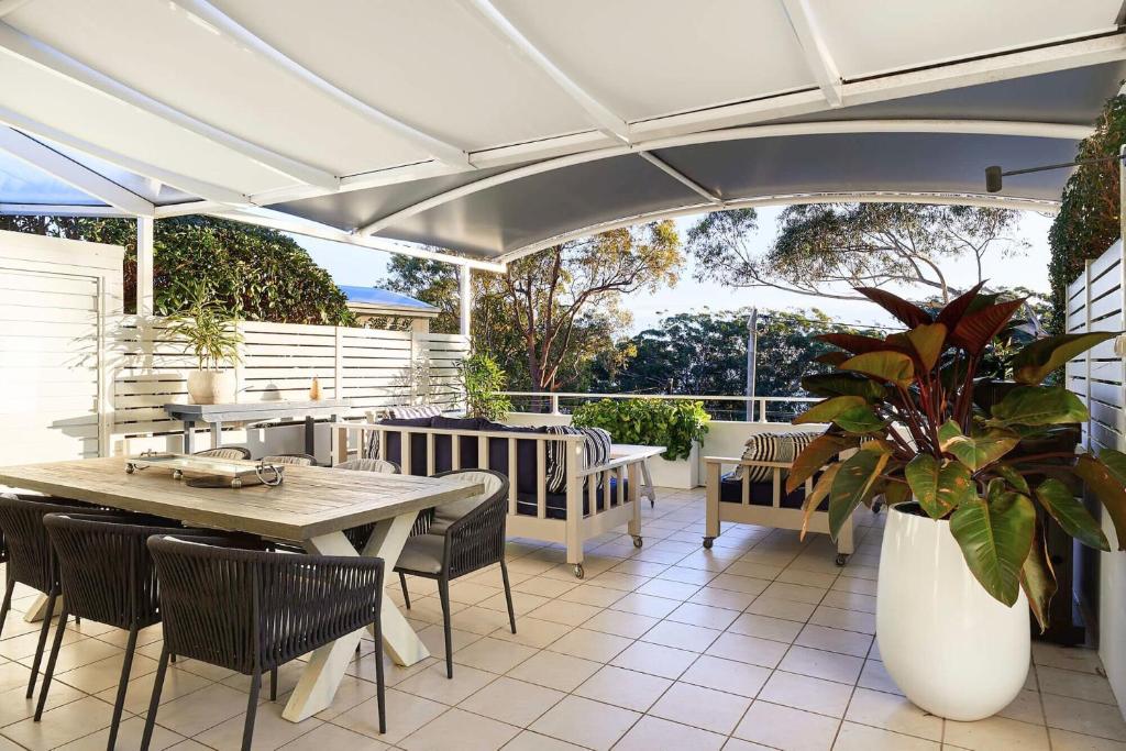 une terrasse avec une table, des chaises et un parasol dans l'établissement Arabella, à Nelson Bay