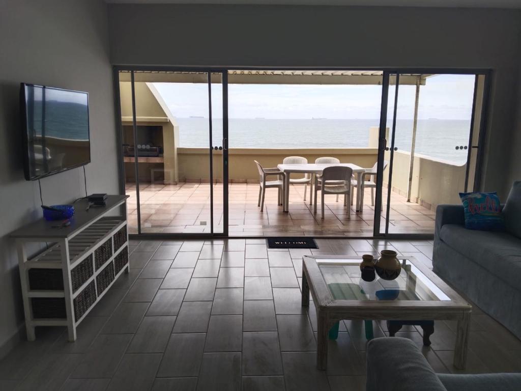 a living room with a table and a view of the ocean at 5 Telena in Umdloti