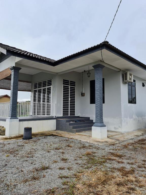 Biały dom z dużym dziedzińcem przed nim w obiekcie Teratak Che Esah Guest House FREE WIFI NETFLIX w mieście Pasir Mas