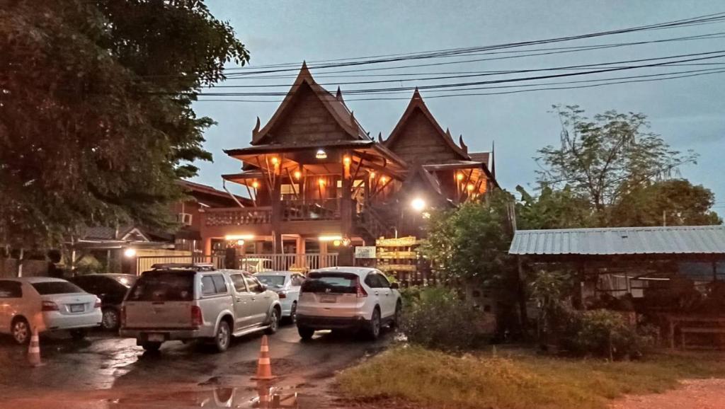 a large building with cars parked in front of it at บ้านเรือนไทยมะลิเมืองเก่า in Sukhothai