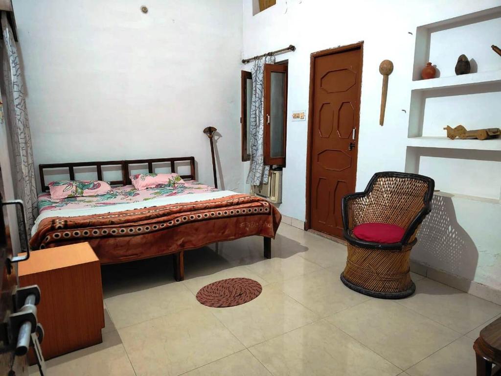 um quarto com uma cama e uma cadeira em Royal Guest House em Bharatpur