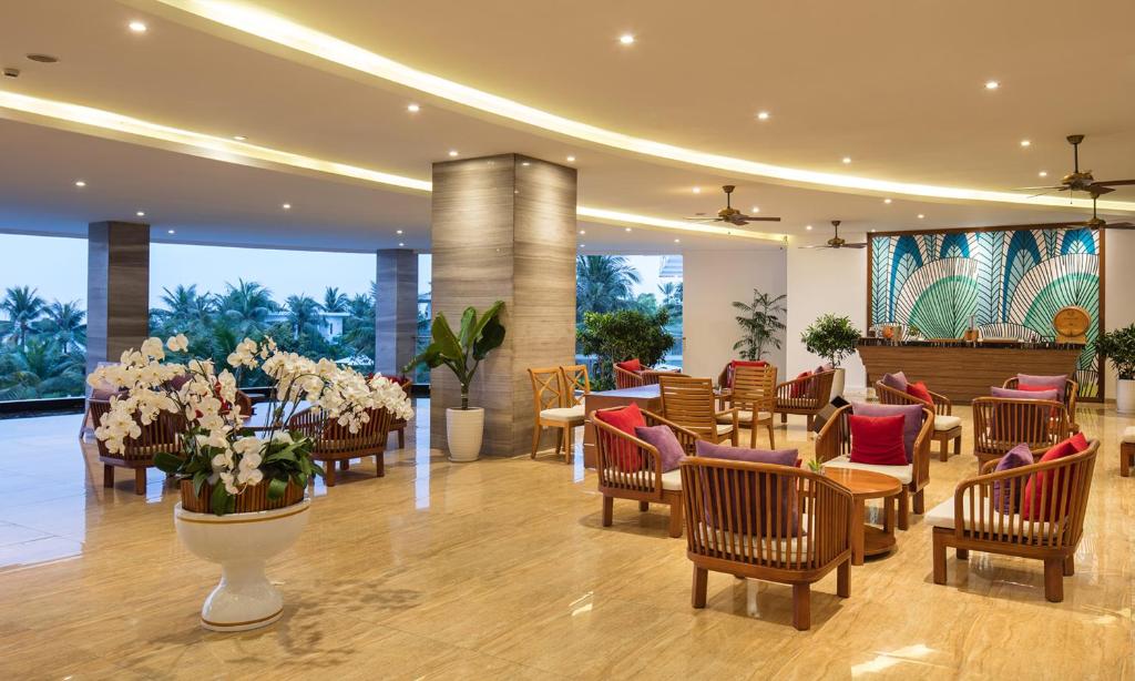a hotel lobby with chairs and tables and flowers at Cam Ranh Riviera Beach Resort & Spa in Cam Ranh