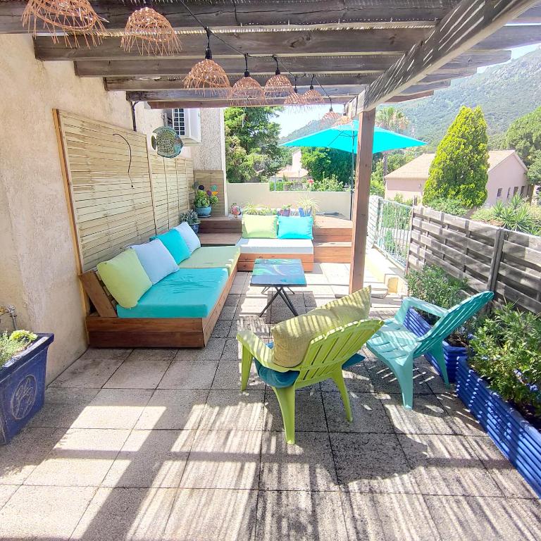 une terrasse avec un canapé, des chaises et un parasol dans l'établissement appartement dans villa aquarelle, à Biguglia