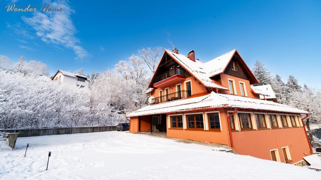 una casa arancione nella neve con alberi coperti di neve di Wonder Home - Apartamenty Karkonosz blisko wyciągów narciarskich, szlaków i restauracji a Karpacz