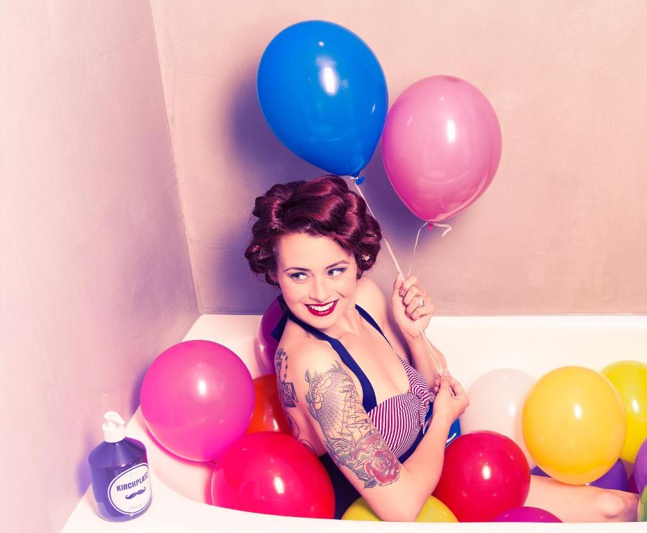 a woman sitting in a bath tub holding a bunch of balloons at Hotel Pension Kirchplatz in Sankt Anton am Arlberg