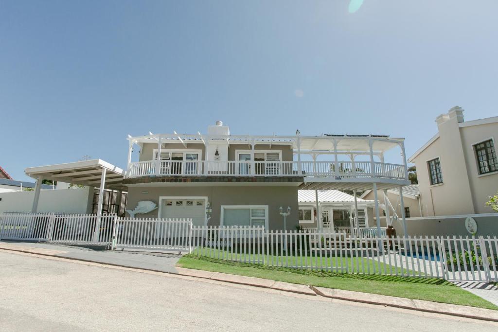 una casa con una cerca blanca delante de ella en Surf n Sea Beachfront Holiday Home, en Jeffreys Bay