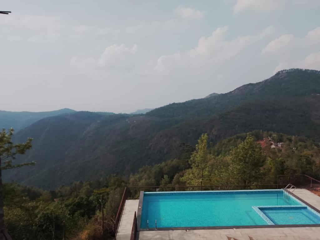 a swimming pool with mountains in the background at Tulip In Green Meadows in Yercaud