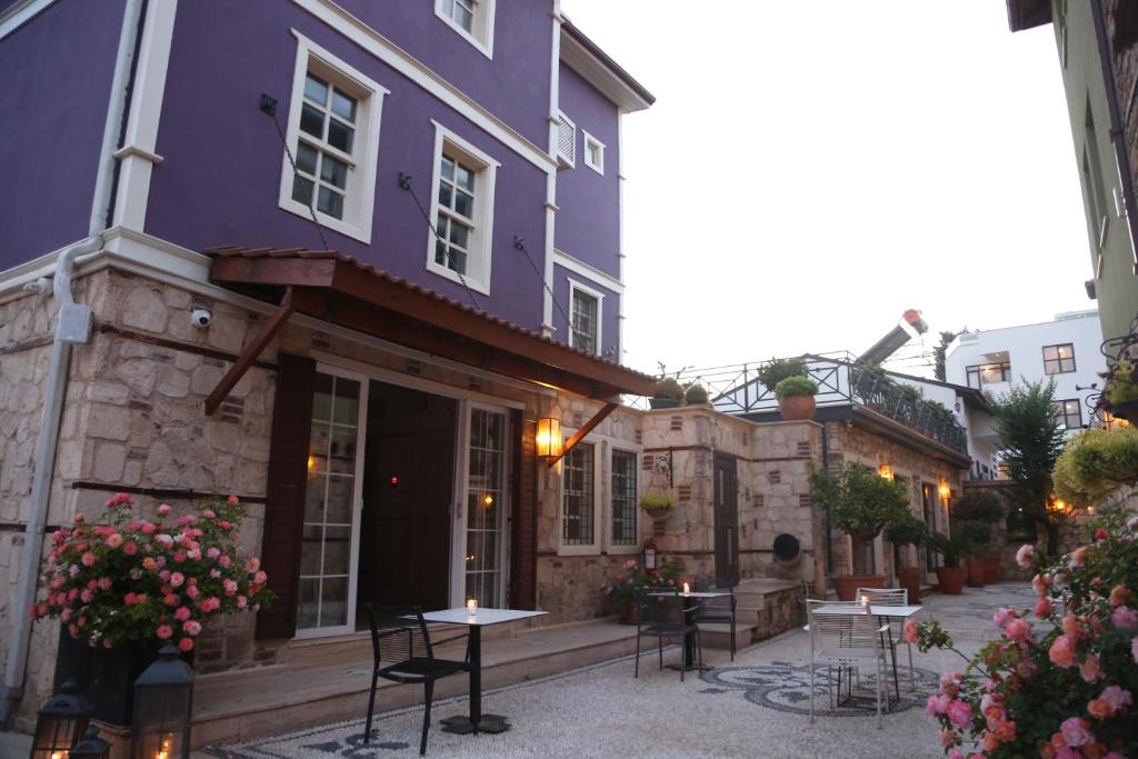 a purple building with tables and chairs in a courtyard at Swim-Up Garden Flat with near Hadrian's Gate in Antalya