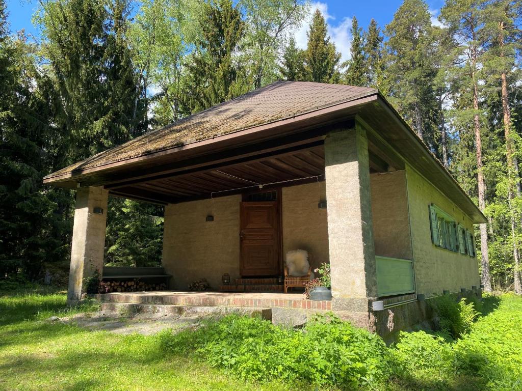 una pequeña casa con un porche en el césped en Mökki merenrannalla Vuosaaressa, en Helsinki