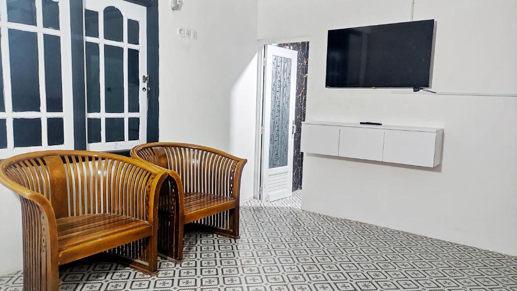 a room with two chairs and a television on a wall at Kost Harian Semarang Murah in Semarang