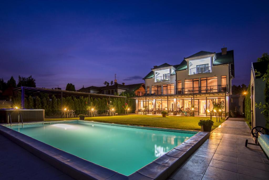 una piscina di fronte a una casa di notte di Guest House Panorama Aqualux a Novi Sad