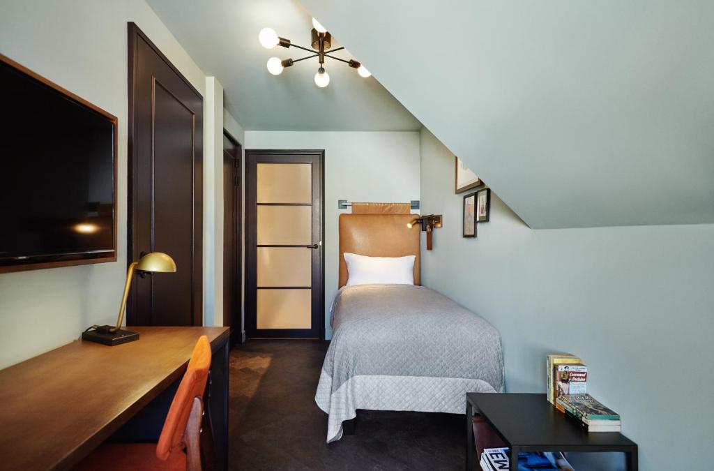 a small bedroom with a bed and a desk at The Hoxton, Amsterdam in Amsterdam