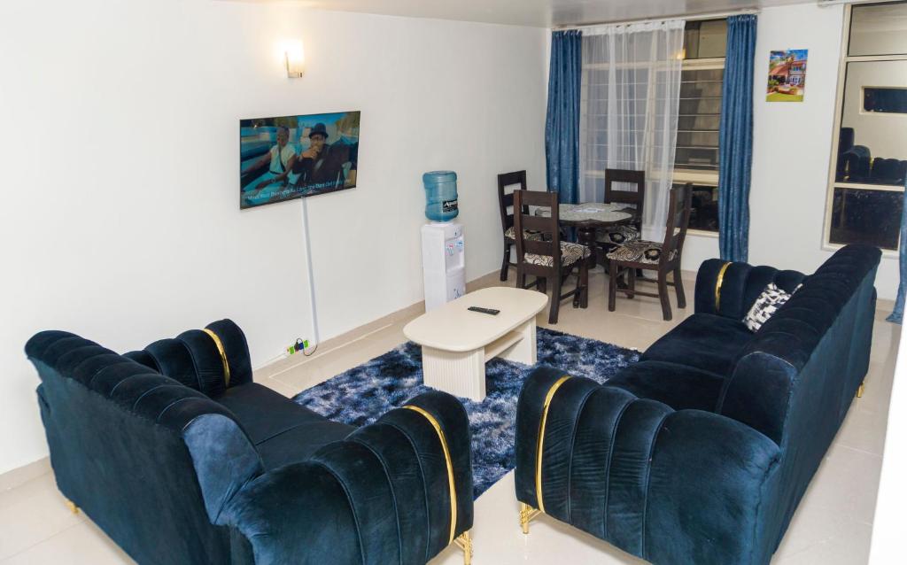 - un salon avec des canapés bleus et une table dans l'établissement CastleHomes 1Bedroom Furnished Apartments, à Ruaka
